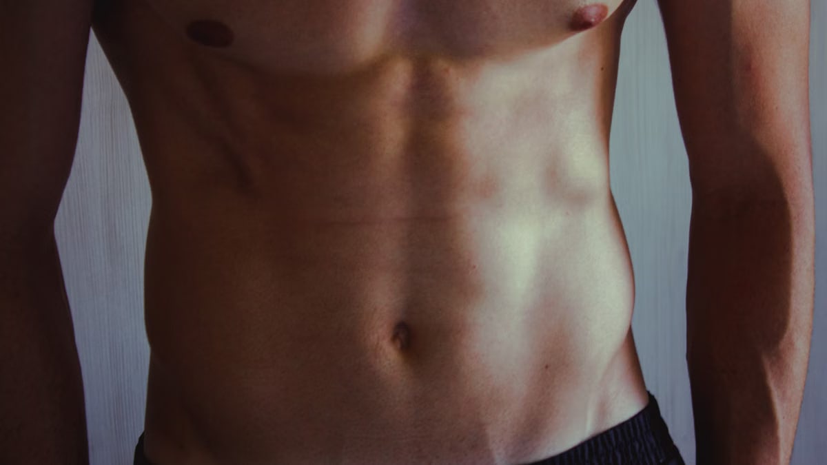 A close-up image highlighting a fit, muscular man's bare torso showcasing toned abs.